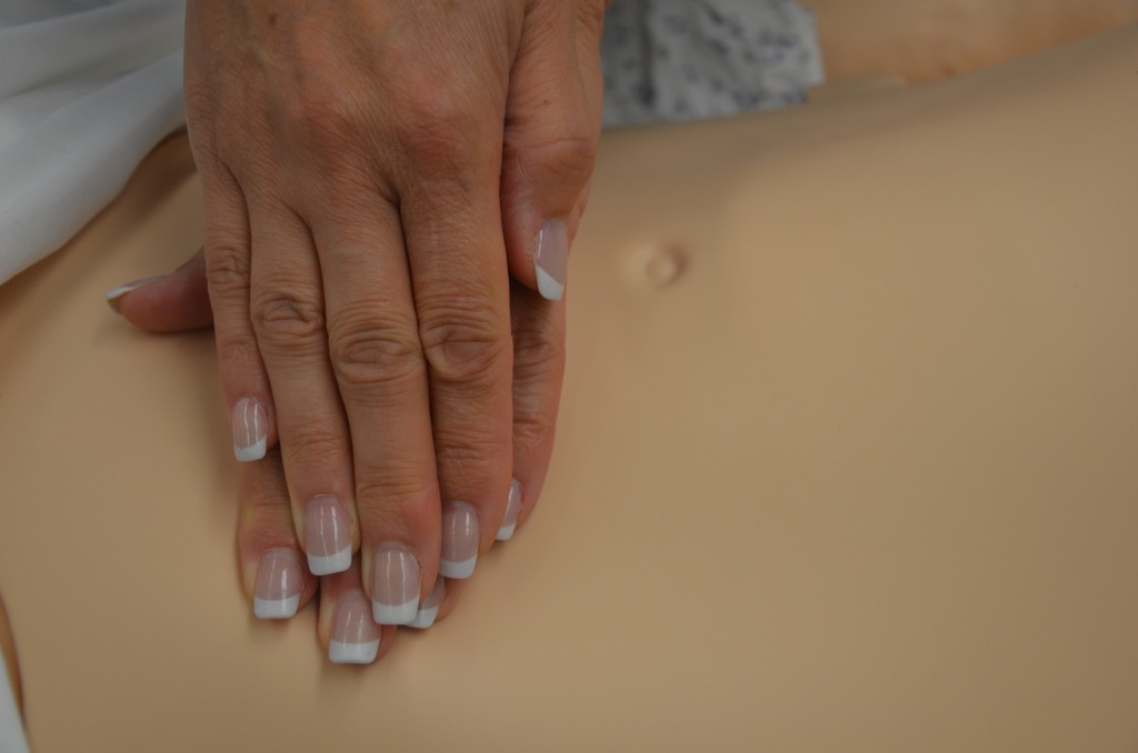 Photo showing hands on a practice mannequin's abdomen