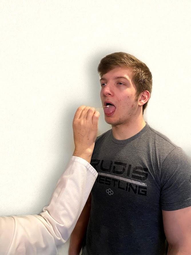 Photo of simulated patient having a cotton swab placed on his tongue by nurse