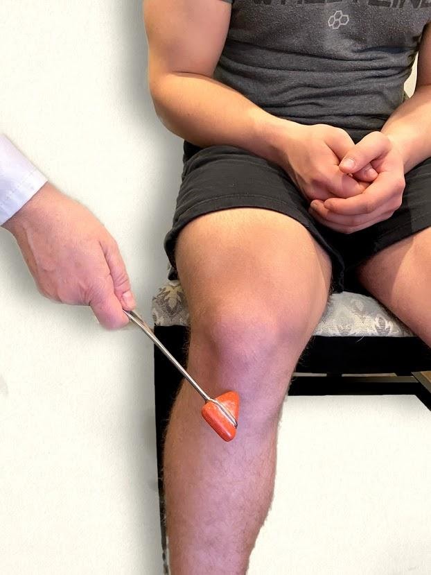 Photo showing a nurse testing the patellar reflex