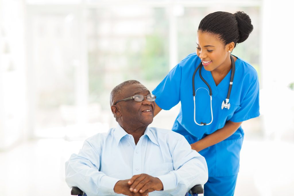 Photo showing a nurse smiling at a patient in a wheel chair